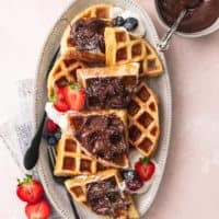 overhead view of platter of belgian waffles with fresh fruit and nutella