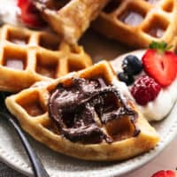 up close view of belgian waffles with nutella, powdered sugar, and fresh berries