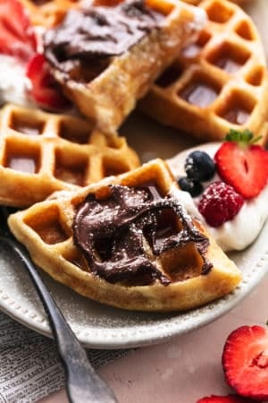 up close view of belgian waffles with nutella, powdered sugar, and fresh berries