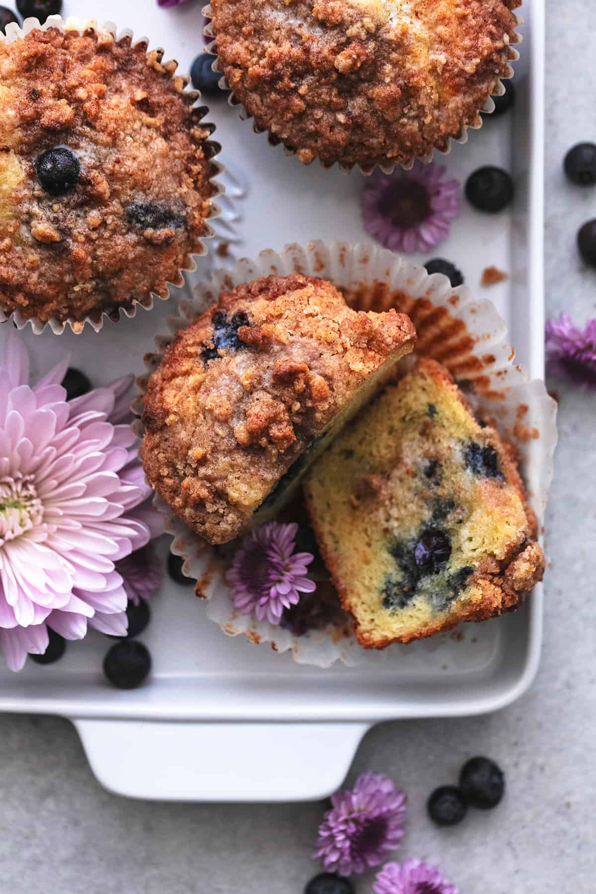 overhead view of blueberry muffin cut in half beside more muffins