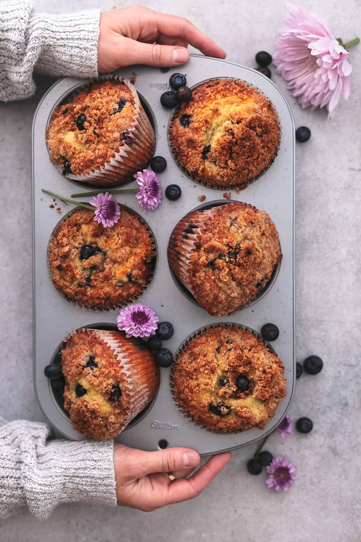 hands holding tray of six muffins
