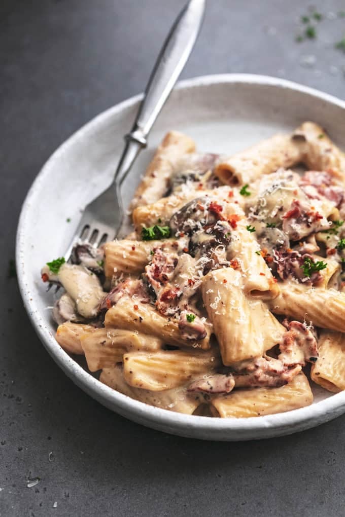 mushroom and bacon pasta on a plate with a fork