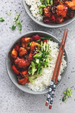 two plates of chinese chicken and vegetables with steamed rice
