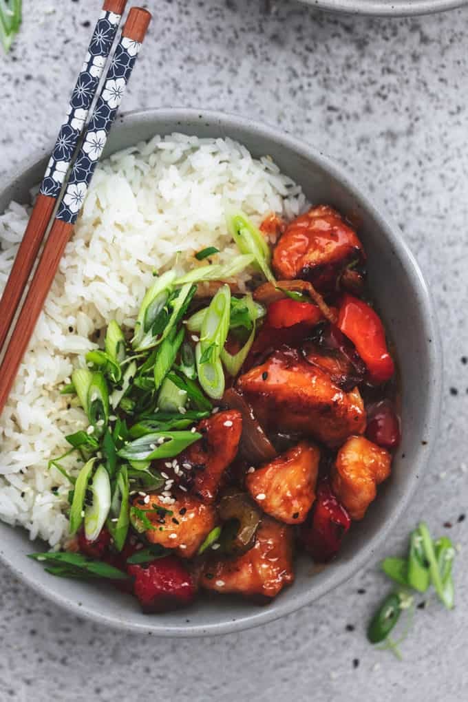 sweet and sour chicken in a bowl with rice and chopsticks