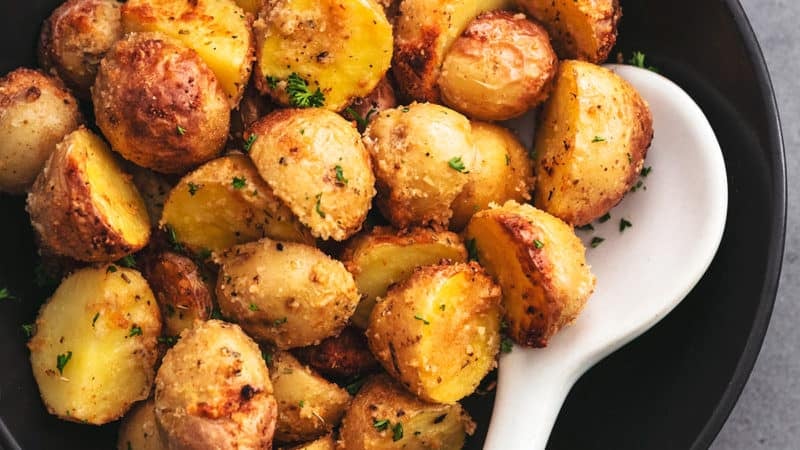 bowl full of crispy potatoes with serving spoon