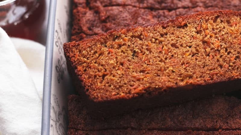 single slice of carrot cake bread on top of more slices in a loaf pan