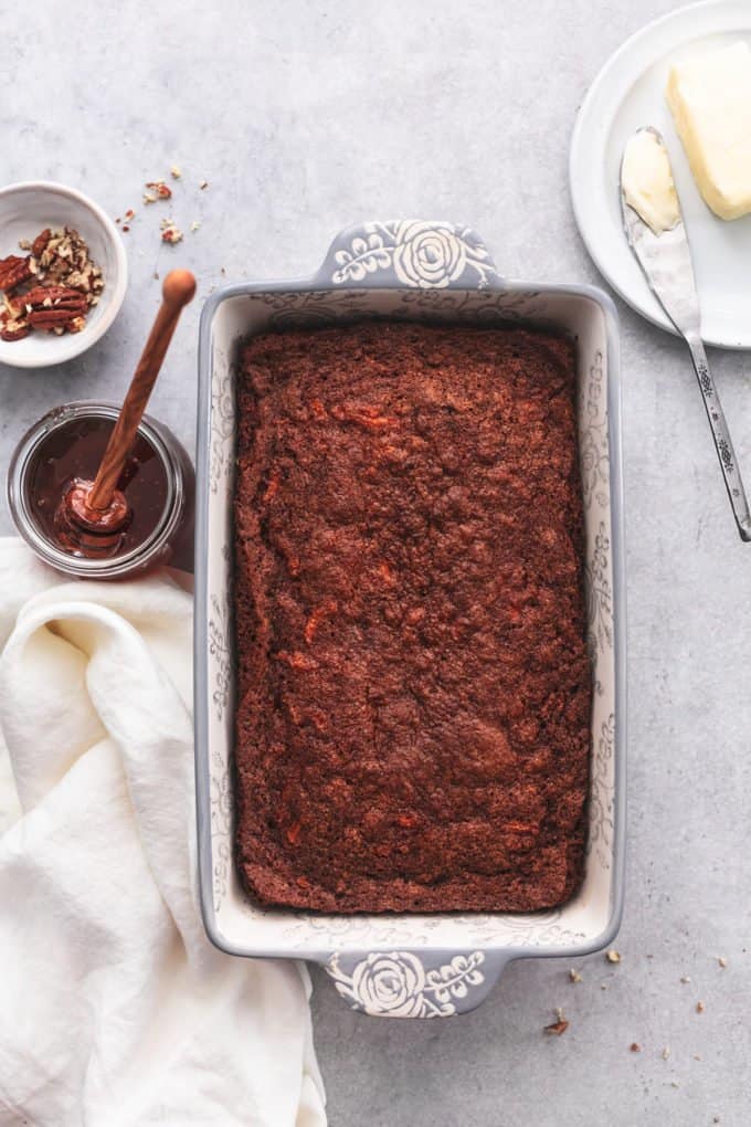 baked carrot bread in loaf pan on table with toppings