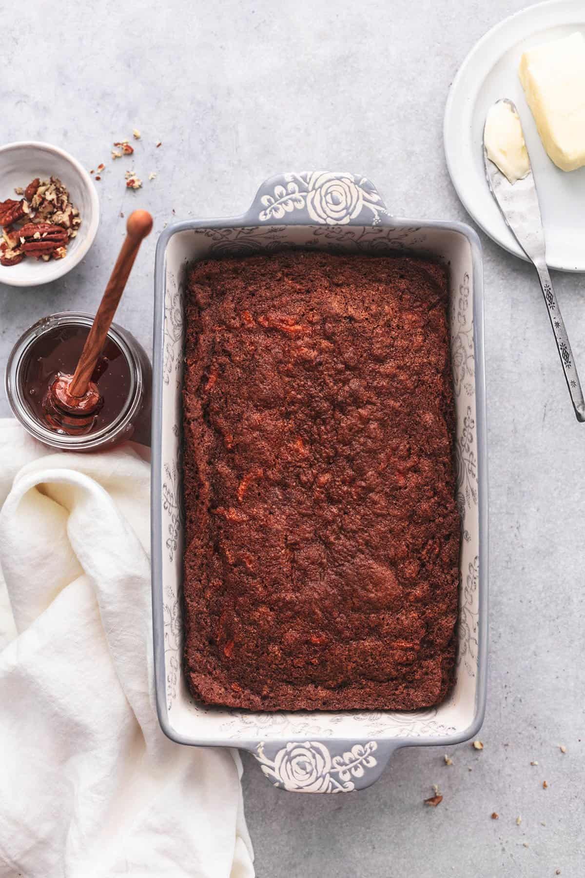 baked carrot bread in loaf pan on table with toppings