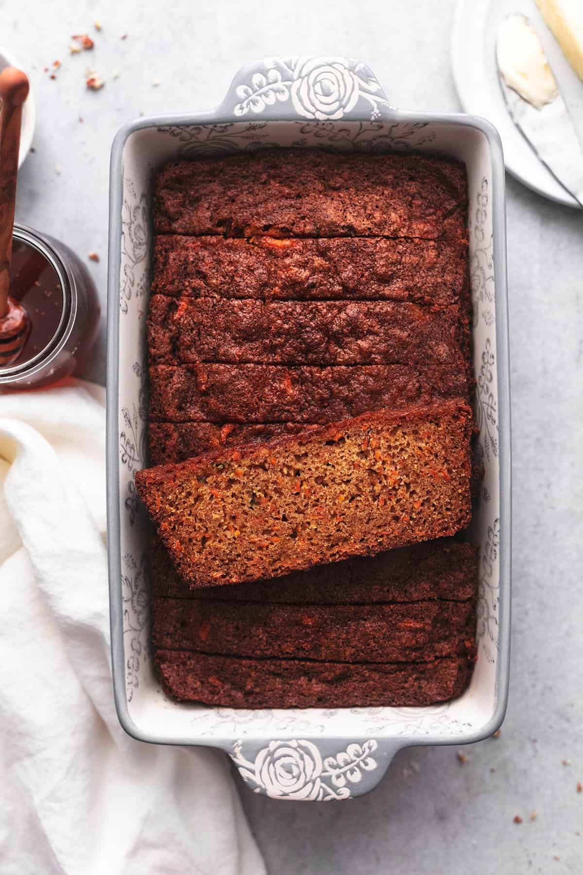 sliced carrot cake bread in baking pan with honey and napkin