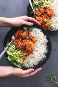 hands holding bowl of shrimp and rice and slaw above second bowl