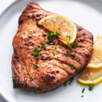 grilled tuna steak on a plate with lemon slices