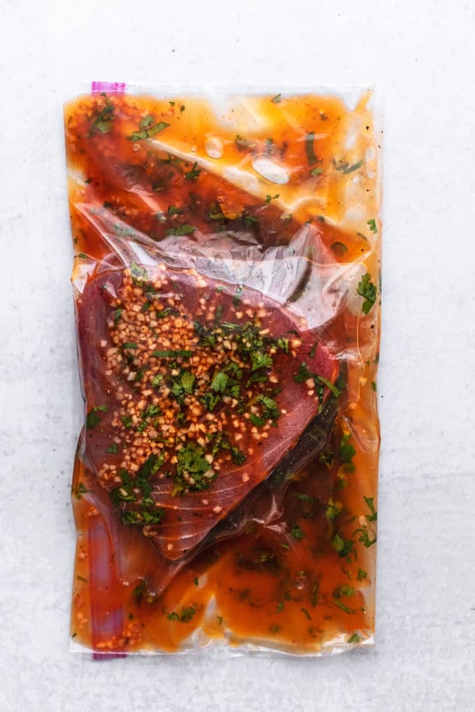 tuna steak in a sealed bag with garlic and herb marinade