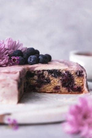 blueberry cake on marble cake stand with flowers and blueberries