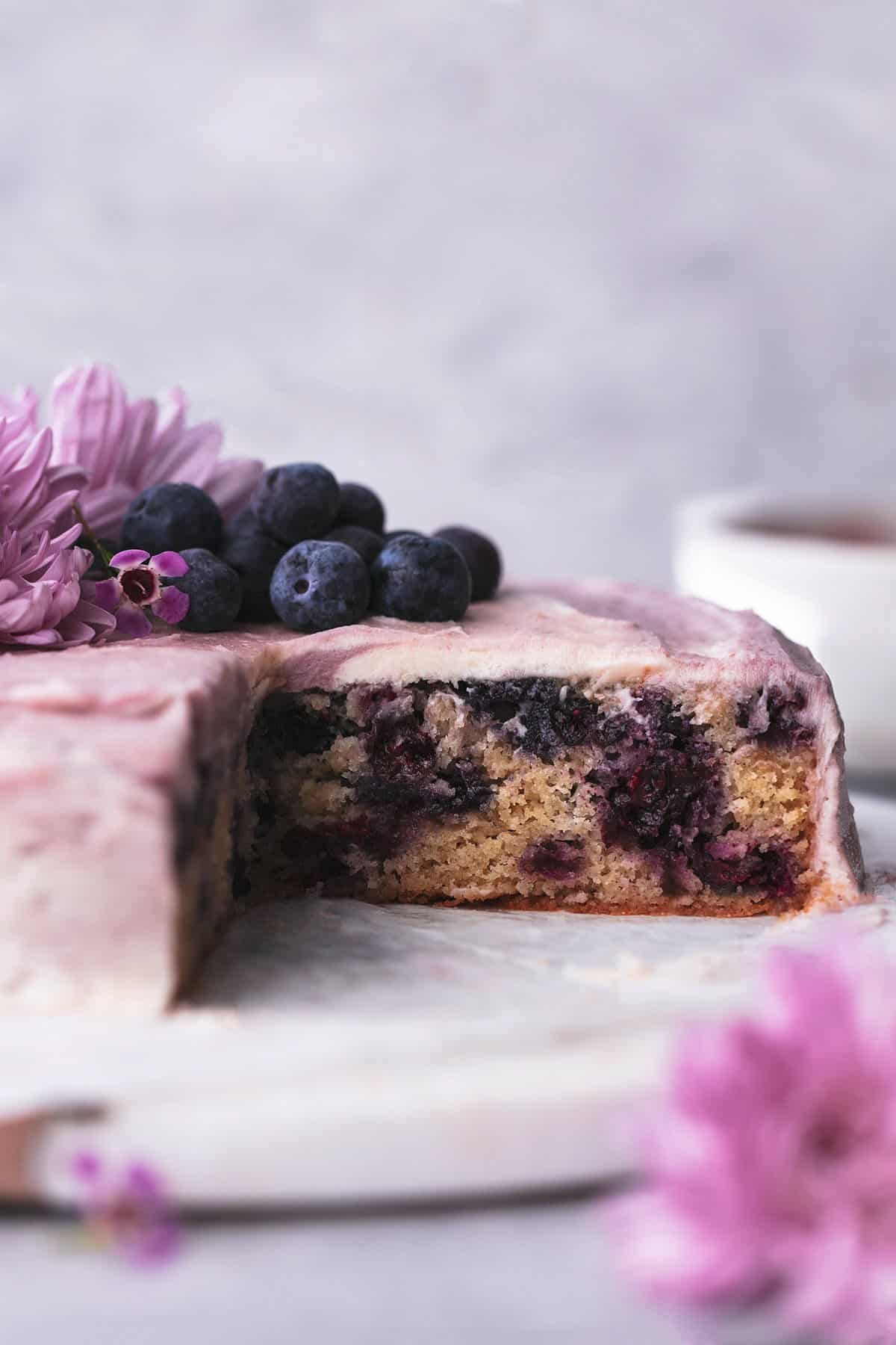 blueberry cake on marble cake stand with flowers and blueberries