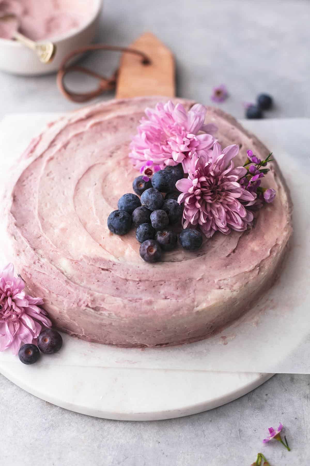 blueberry cake with flowers and blueberries on a marble cutting board