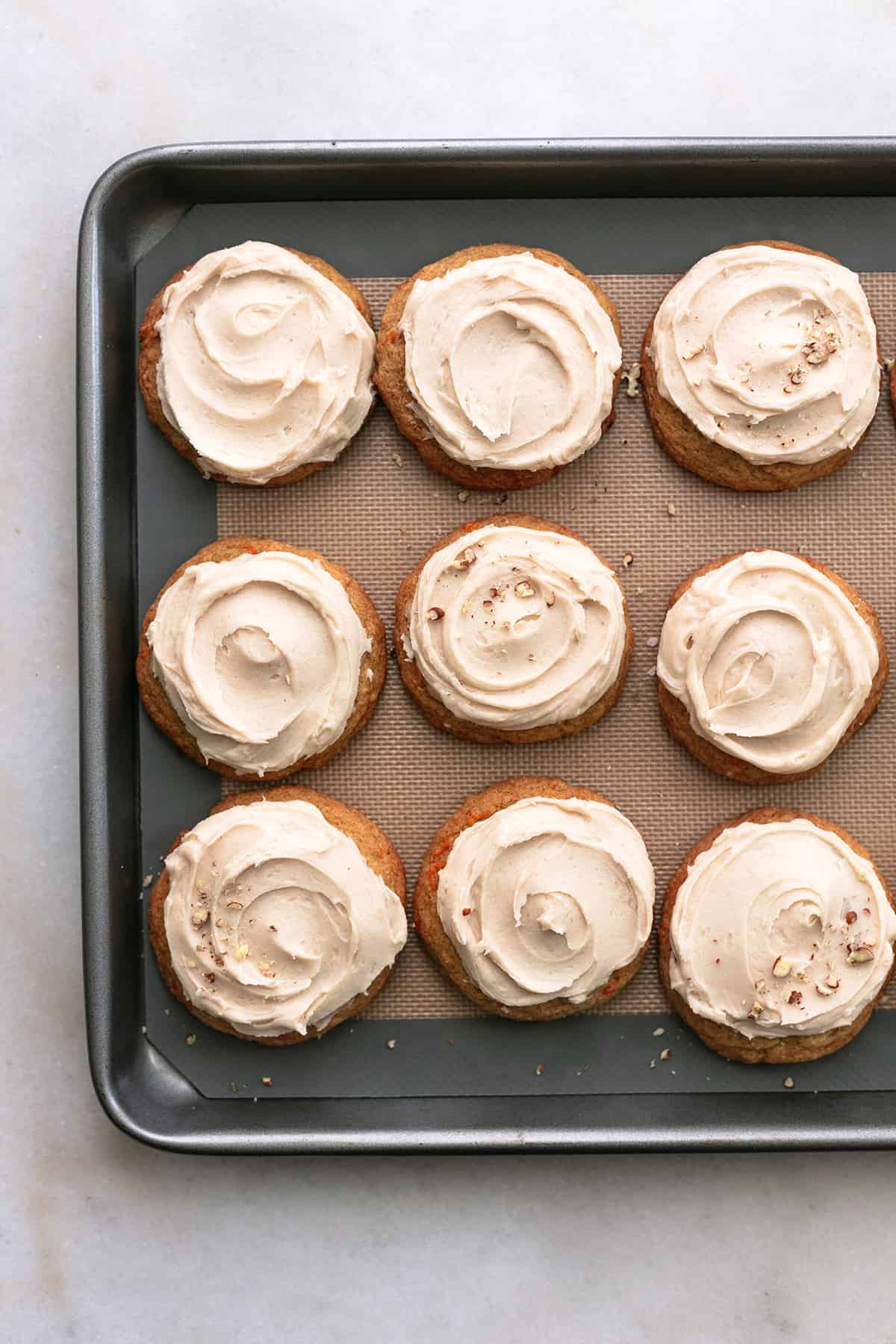 overhead view of frosted cookies on a baking sheet