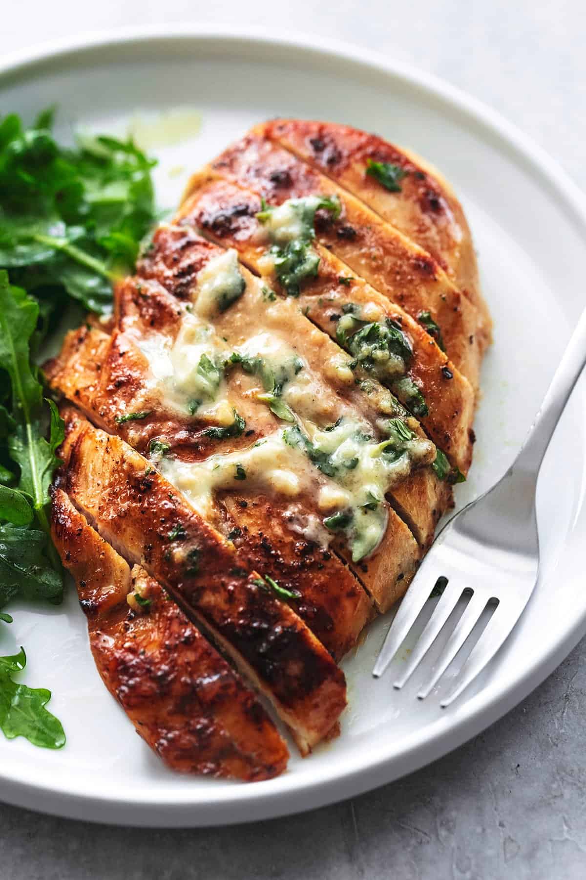 sliced chicken breast with fork and salad on the side