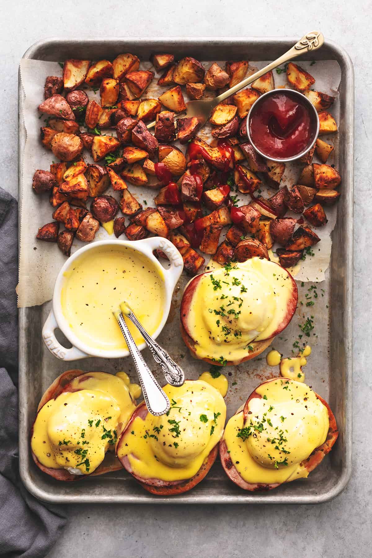 overhead view of potatoes and eggs benedict on sheet pan