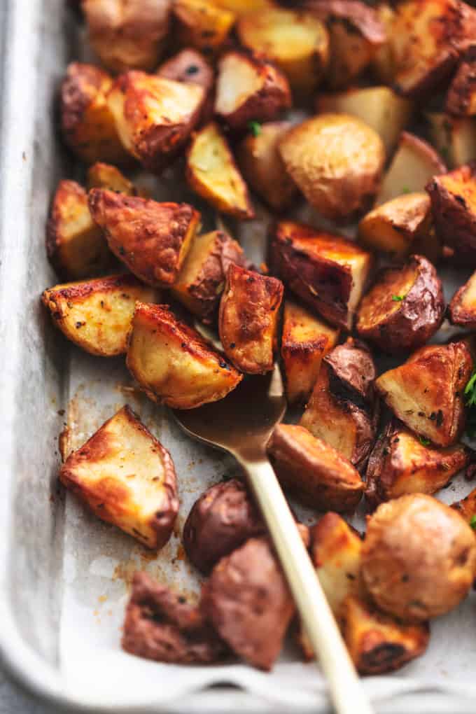 crispy roasted potatoes on a sheet pan with a fork