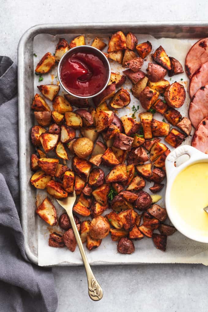 crispy roasted potatoes on a sheet pan with ketchup and a fork