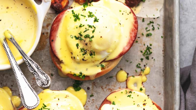 eggs benedict with hollandaise sauce and potatoes on a sheet pan