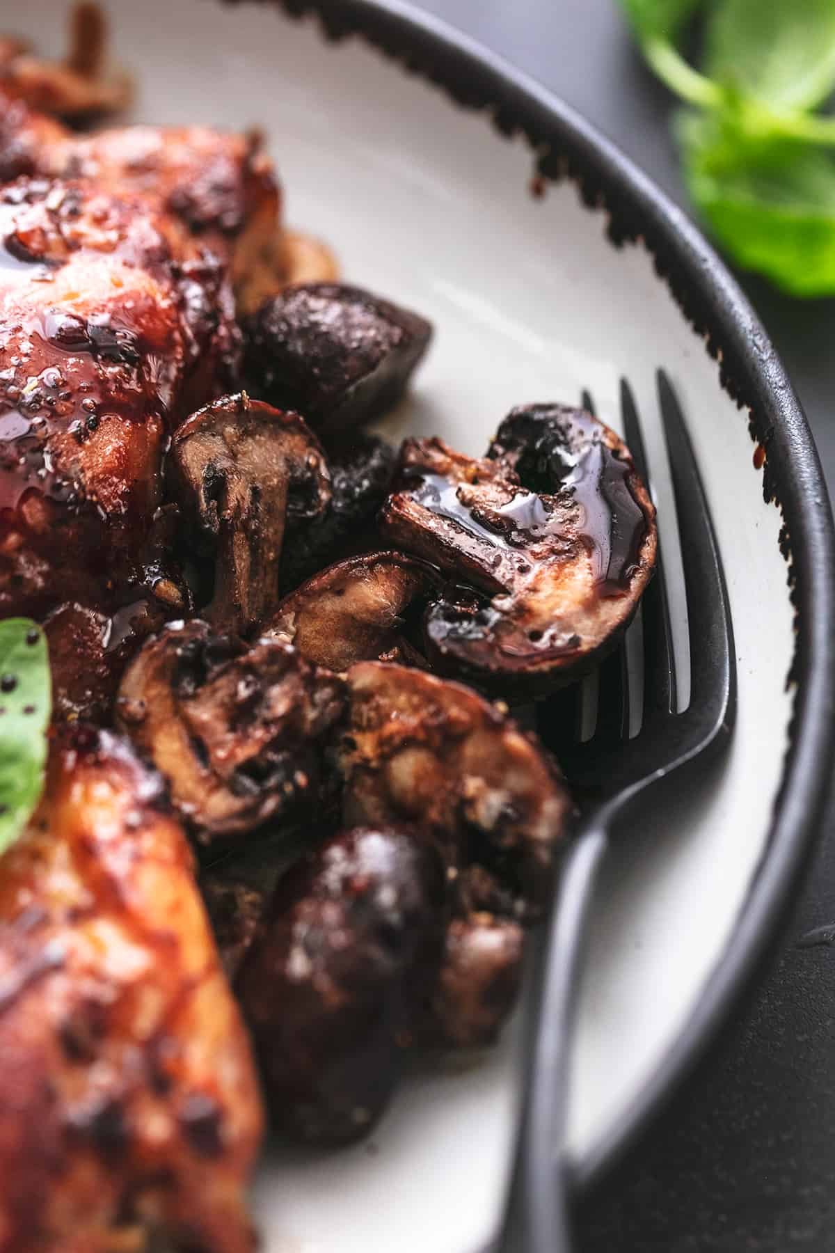 fork with balsamic mushrooms on plate beside chicken