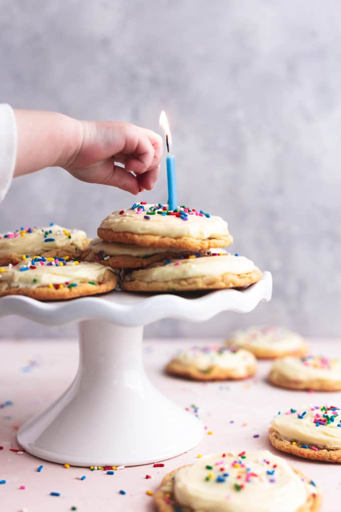 child's hand dropping sprinkle onto cookies