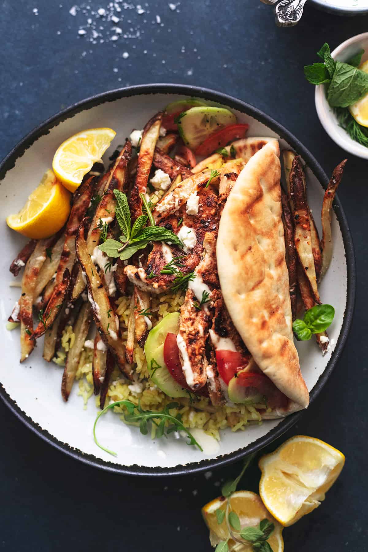 plate of chicken and rice with pita bread and greek fries