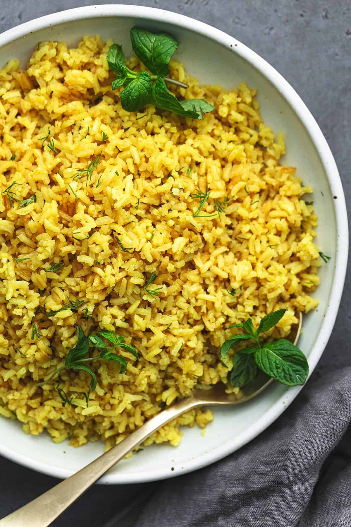 lemon rice with fresh herbs in a bowl with a spoon