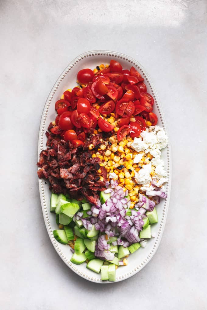 deconstructed salad with corn, bacon, onions, cucumber, tomatoes, and feta cheese