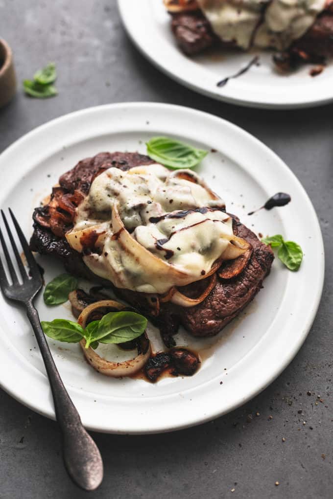 steak topped with cheese and onions with balsamic drizzle