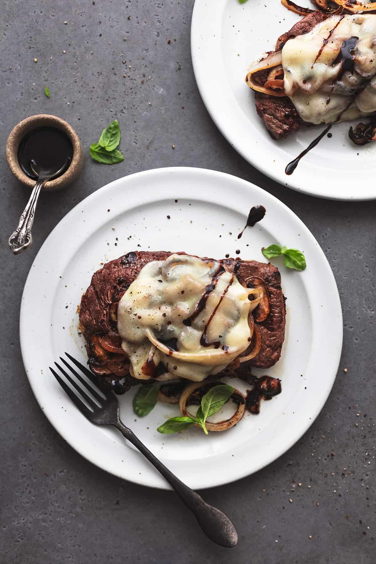 overhead view of steak on a plate with fork and partial second plate