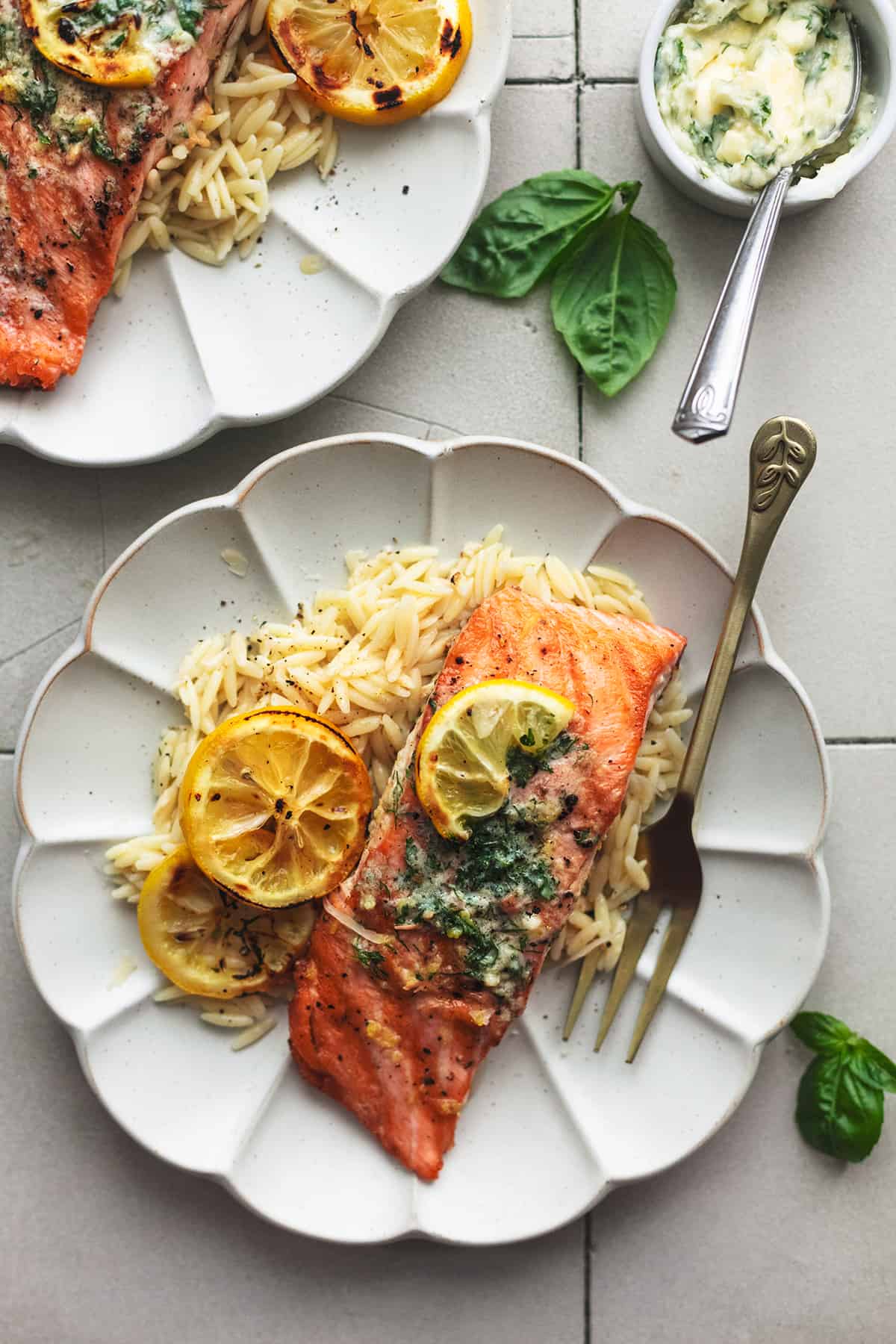 salmon with lemons and orzo on two plates