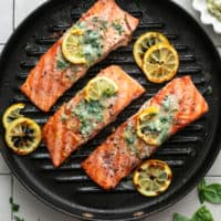 salmon fillets with butter and lemon slices on a grill pan