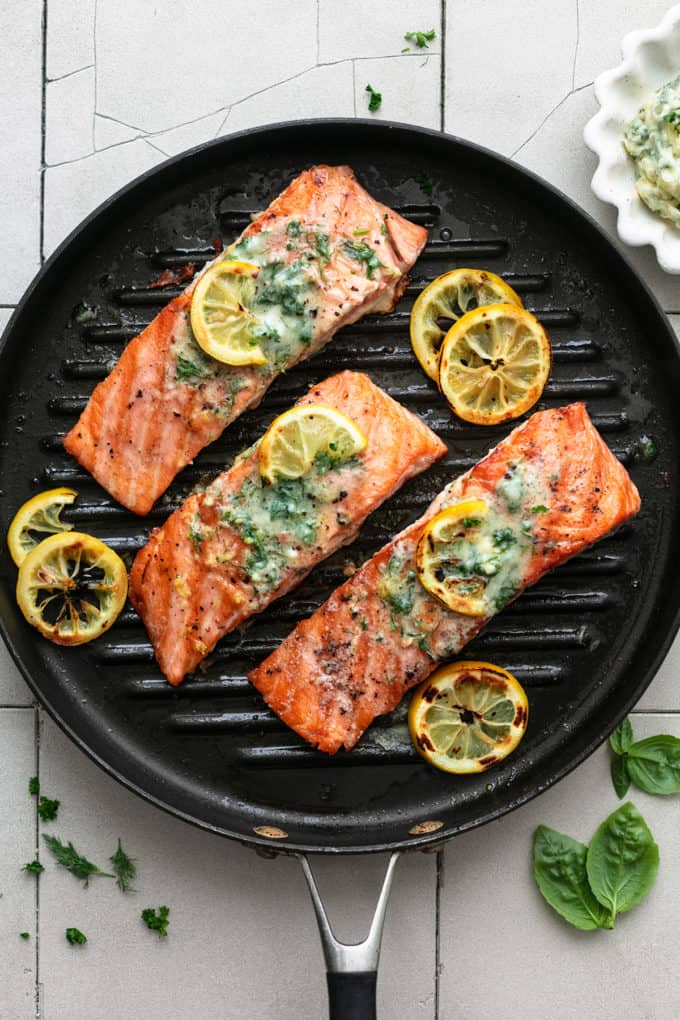 salmon fillets with butter and lemon slices on a grill pan