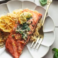 grilled lemon butter salmon with fork and orzo on scalloped plate