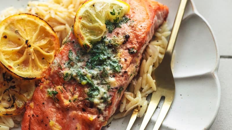 grilled lemon butter salmon with fork and orzo on scalloped plate