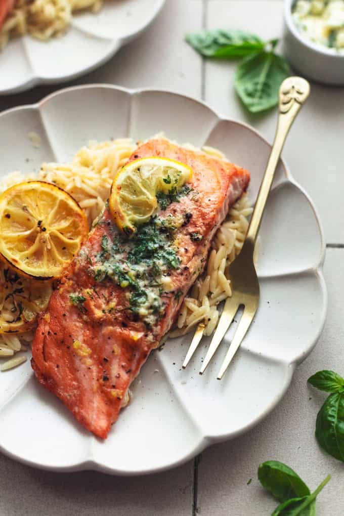 grilled lemon butter salmon with fork and orzo on scalloped plate