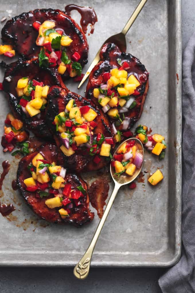 Glazed pork chops with peach salsa on top in a baking sheet.