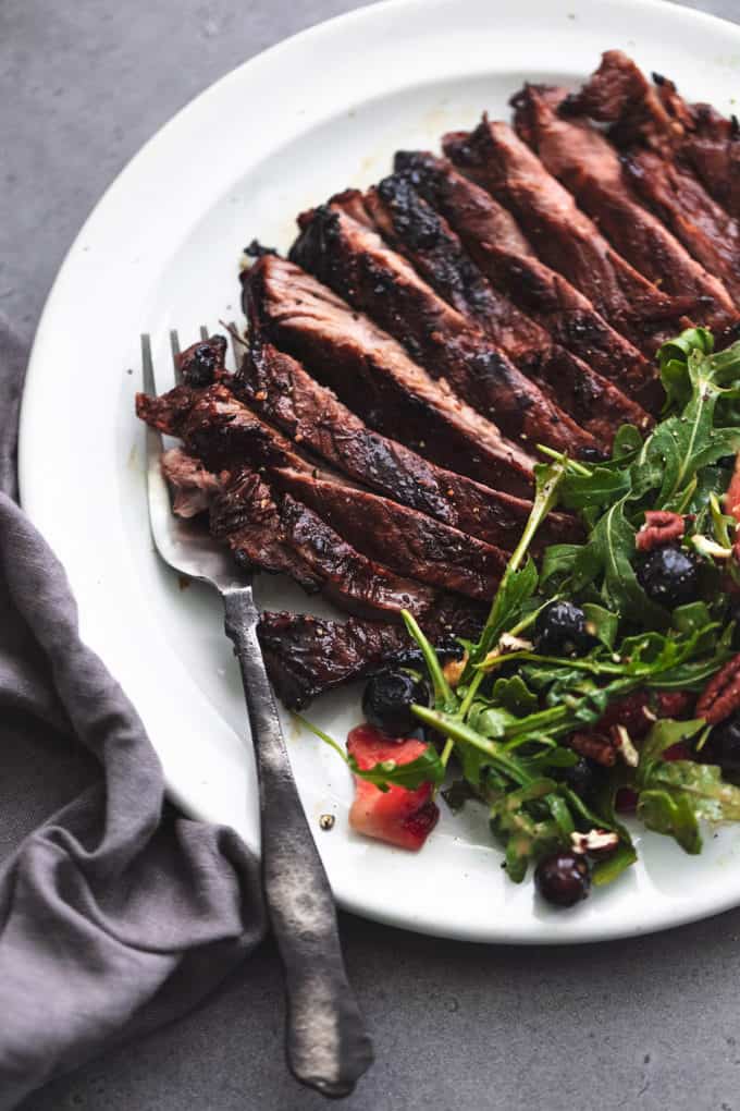 fork on plate with marinated flank steak and green salad
