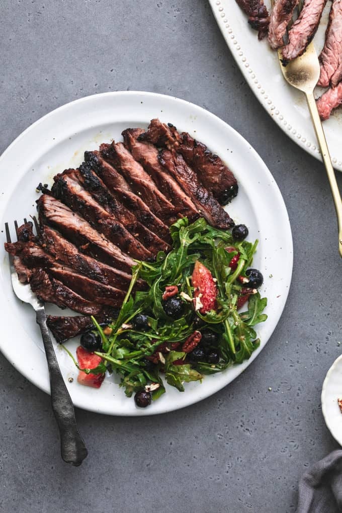 plate of steak with salad beside serving platter of more steak