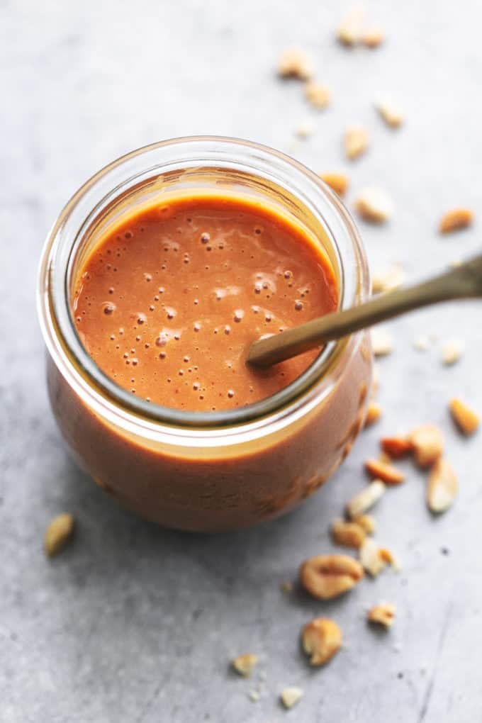 thai peanut dressing in small jar with peanuts in background