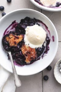 single bowl of blueberry cobbler with ice cream and spoon