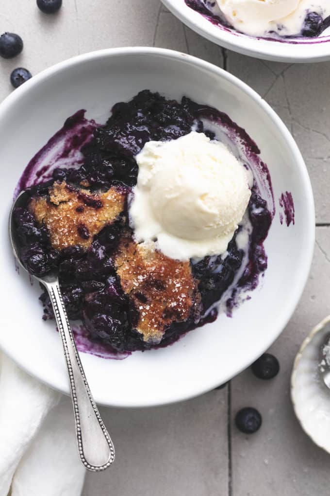 Blueberry cobbler in a bowl with a scoop of ice cream on top. 
