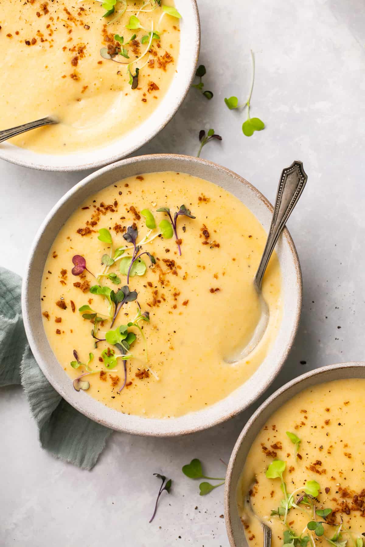 overhead view of three bowls of creamy soup in bowl with herb and bacon garnish