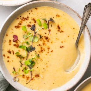 overhead view of potato soup in bowl with spoon and herb garnish