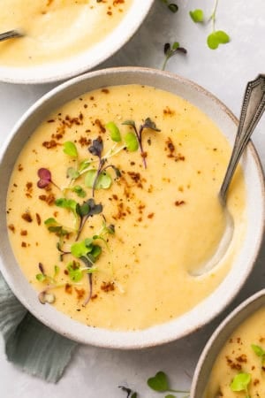 overhead view of potato soup in bowl with spoon and herb garnish