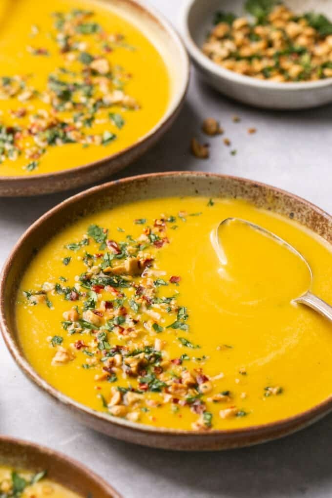 bowl of butternut squash soup with garnish and spoon