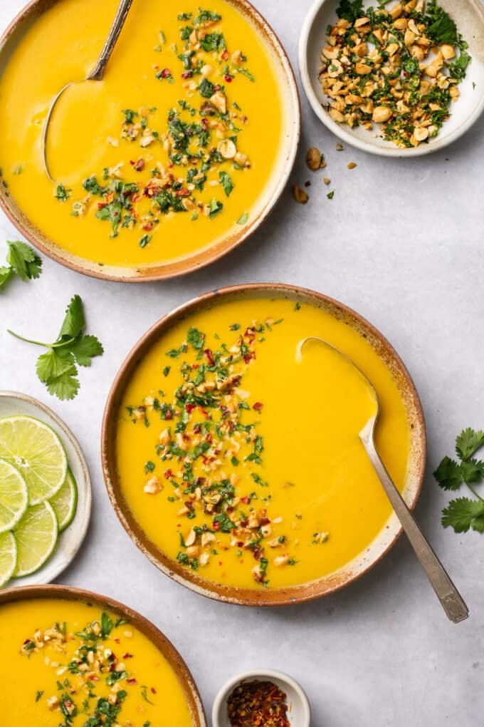 three bowls of butternut squash soup with peanut topping