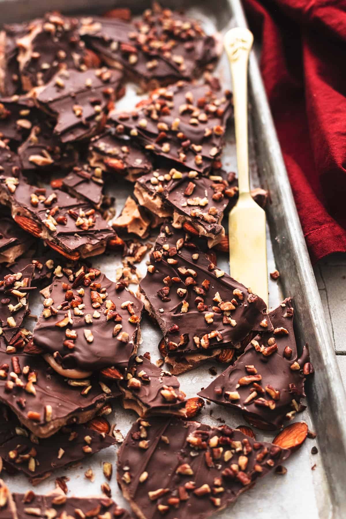 english toffee with almonds and chocolate in pieces on a baking sheet